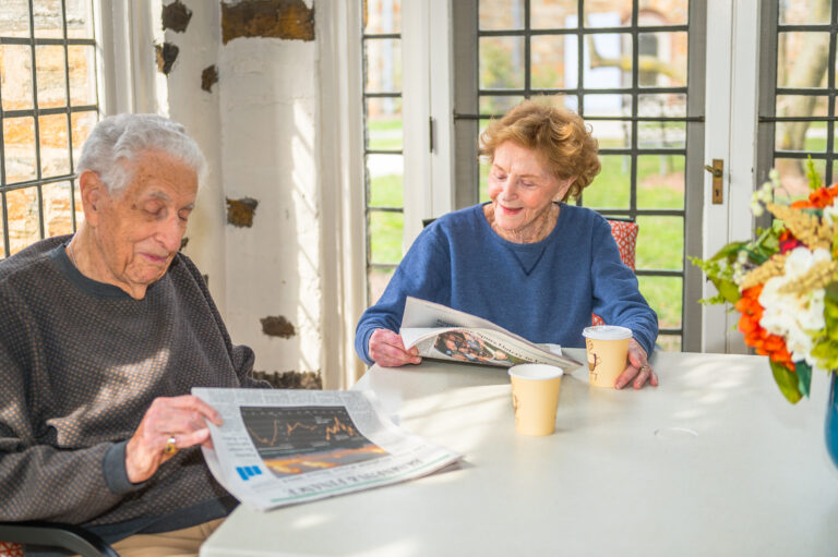seniors reading newspaper at table