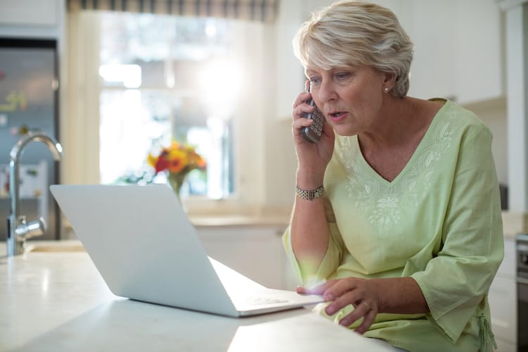 Woman being targeted by senior scams on the phone and computer.