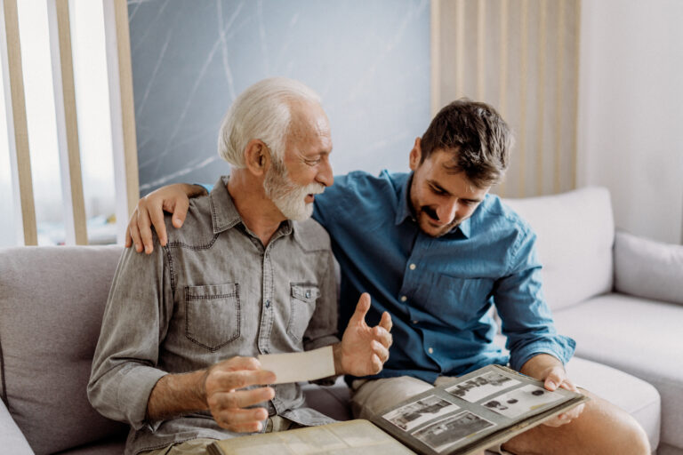 Senior man showing photographs to his son