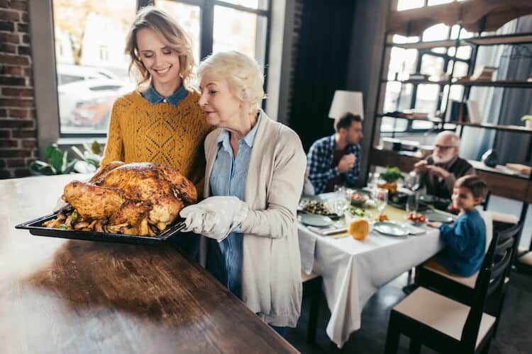 Senior woman and adult daughter preparing the table for a Thanksgiving meal.