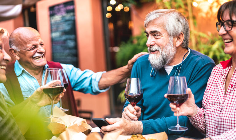 Happy senior friends having fun drinking red wine at dinner party