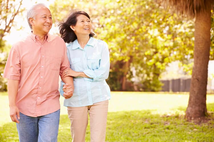 Senior couple walking through park together.